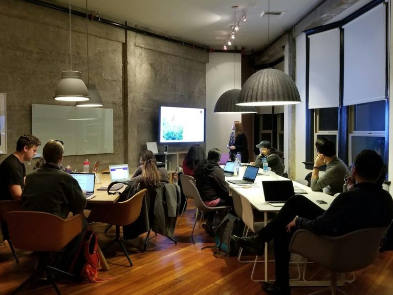 Gruppenarbeit in einem modernen Raum mit mehreren Personen an Laptops.
