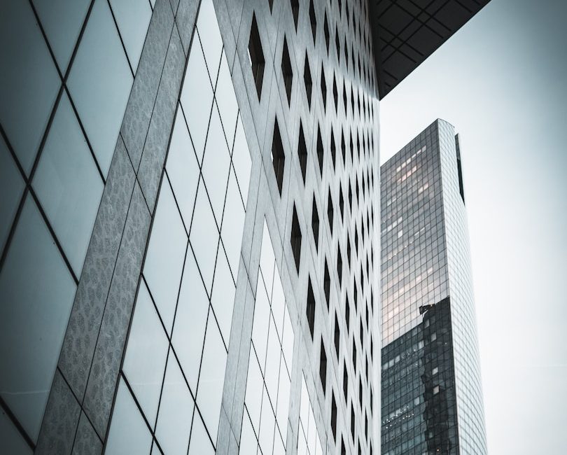 Moderner Wolkenkratzer mit reflektierenden Glasfassaden und geometrischen Mustern.